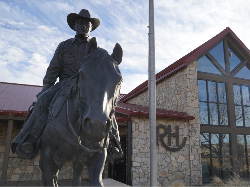 Front of the Ranching Heritage Center with a flag pole and statue of cowboy on a horse